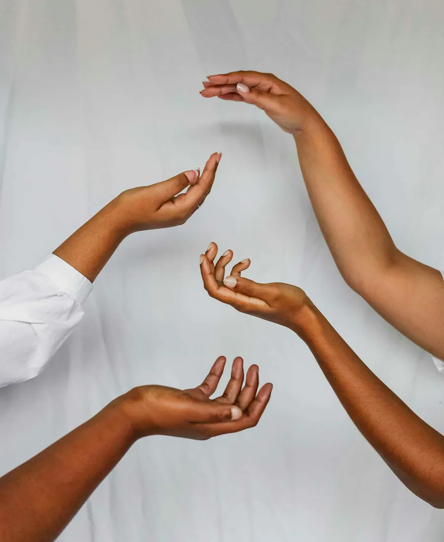 Several open hands reaching towards each other against soft white fabric