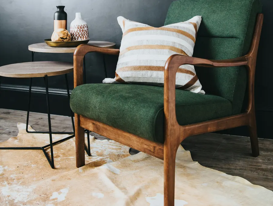 A dark green armchair beside a small side table in a calm room