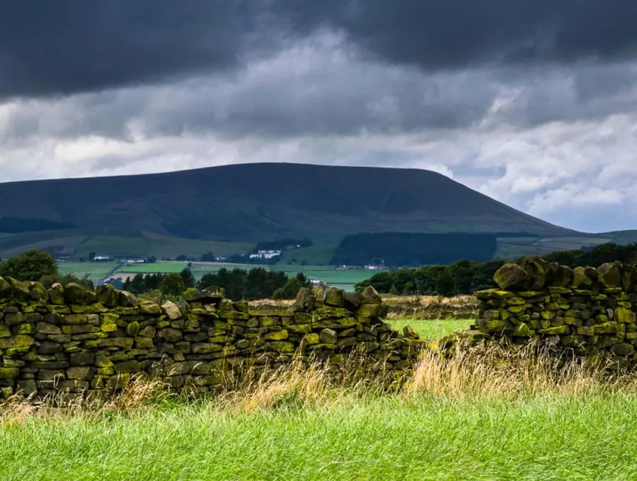 Green hills under a broad sky with a stone wall in the foreground