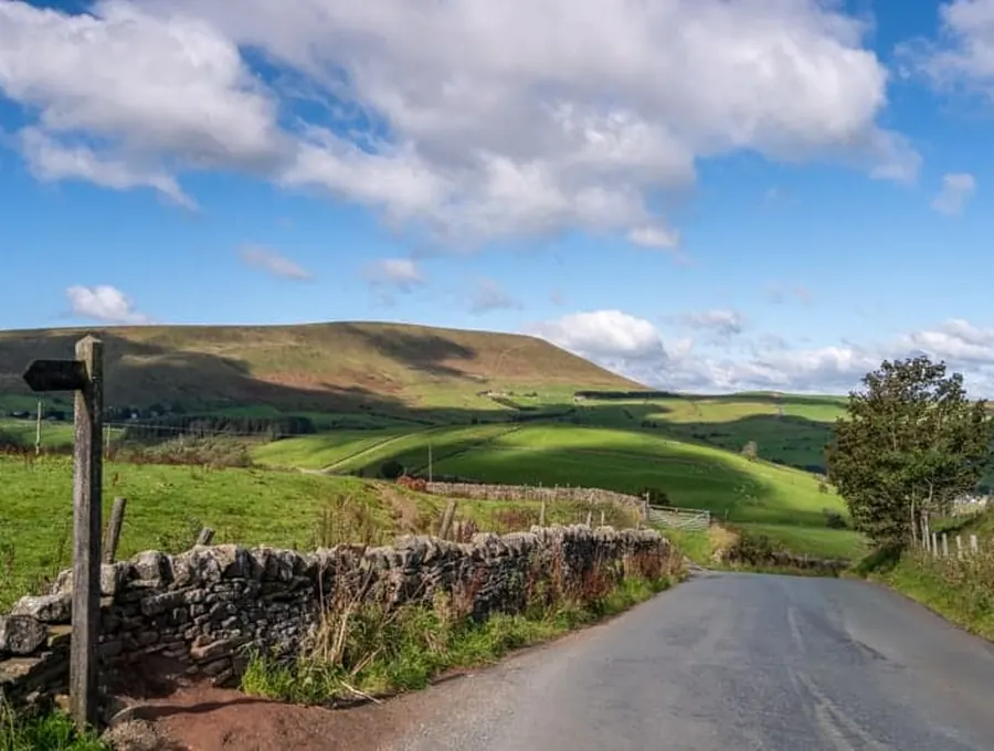 A quiet country road winding through green hills under a wide sky
